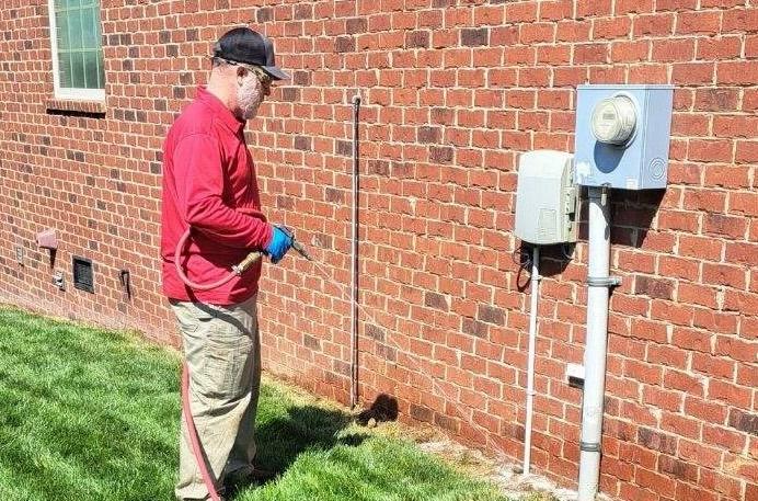 Critter Wranglers technician performing exterior pest treatment